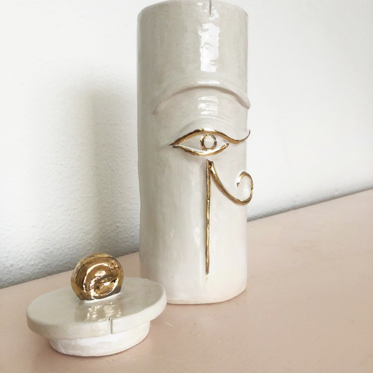 Handcrafted off-white ceramic urn featuring the Eye of Ra on the front in 24-carat gold relief.