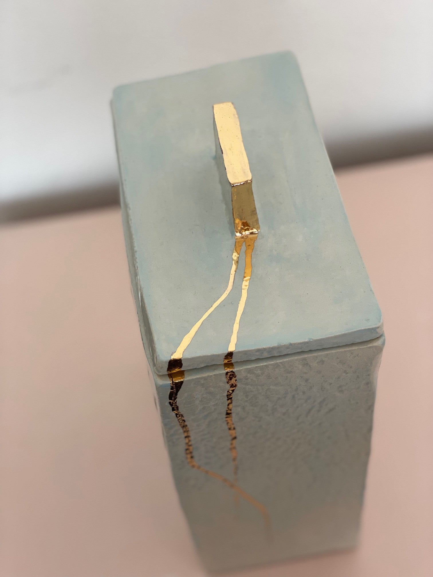 Details van het deksel van een blauwe keramische gedenkurn met gouden details.