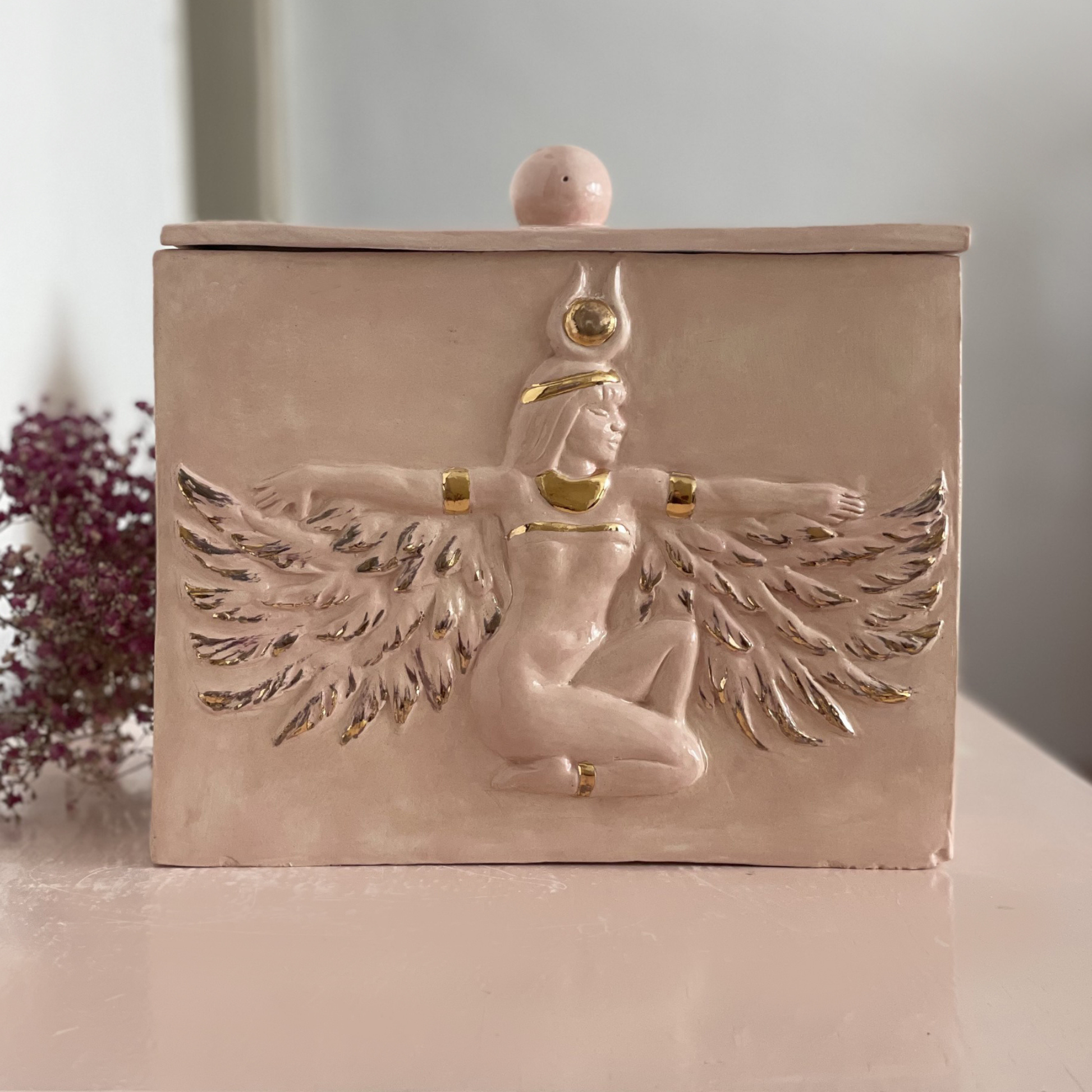 Handcrafted rosé ceramic urn with Isis relief and 24-carat gold details.