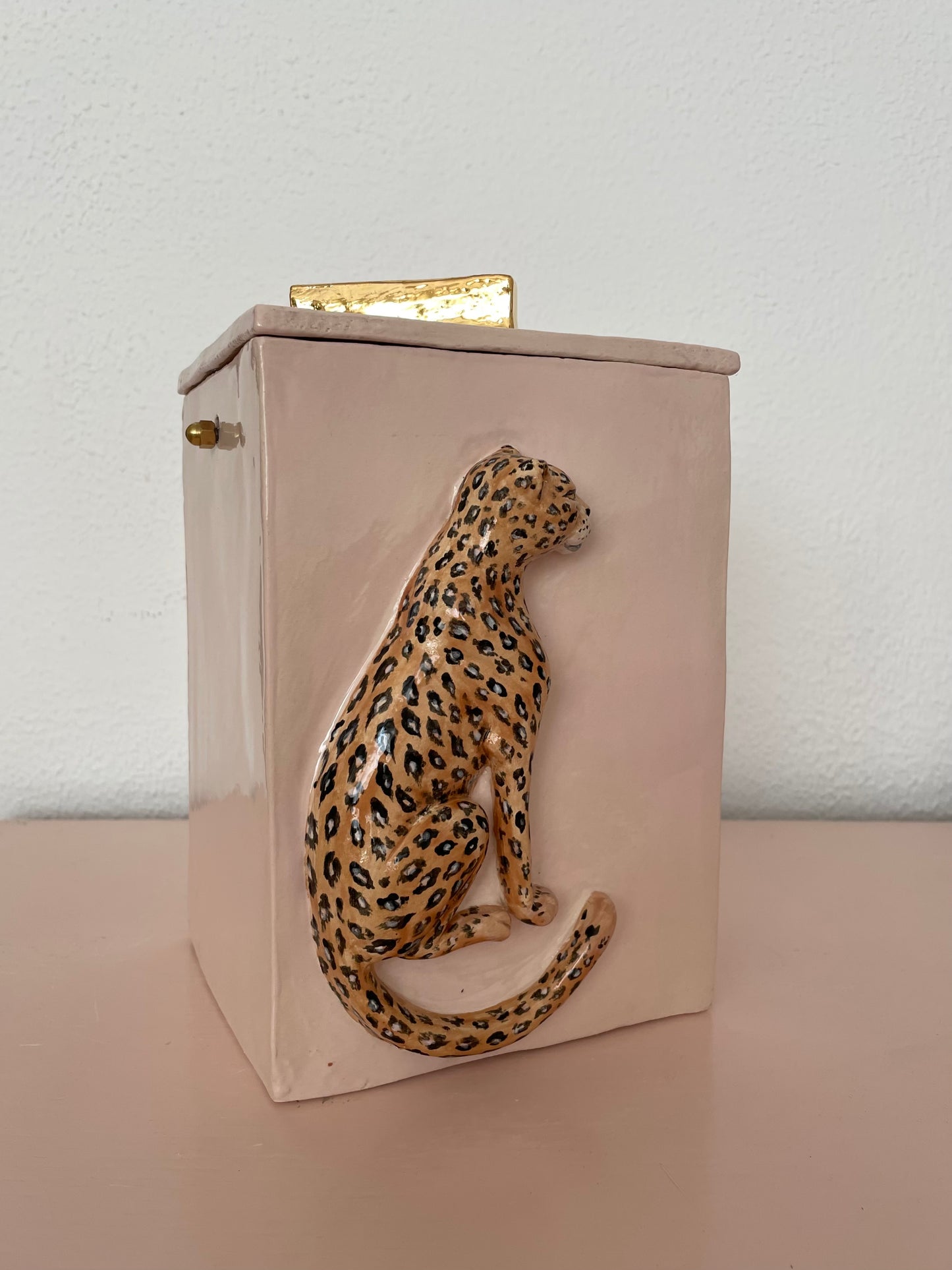 Gedenkurn in roze met dierenprint en gouden details.