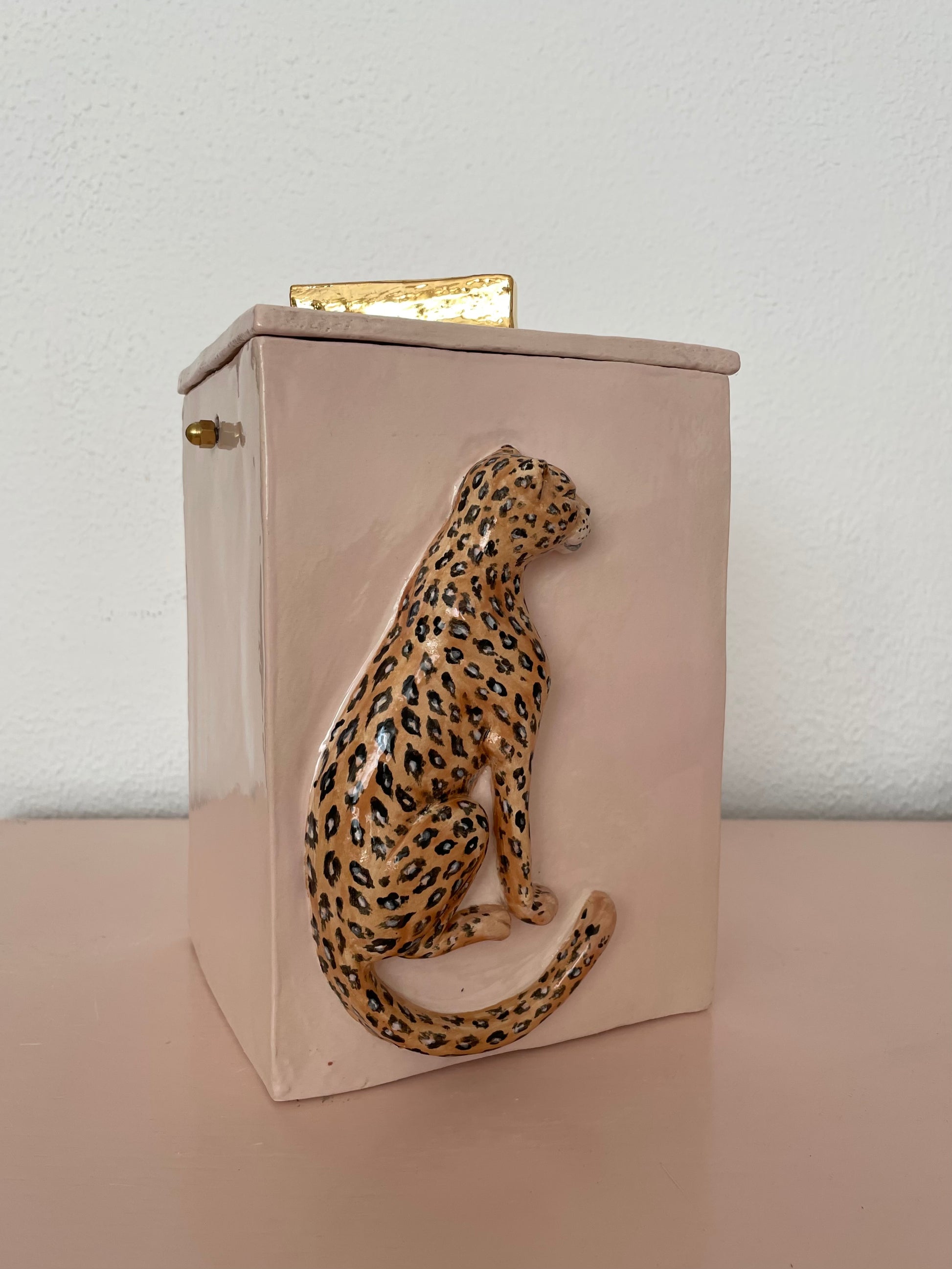 Gedenkurn in roze met dierenprint en gouden details.