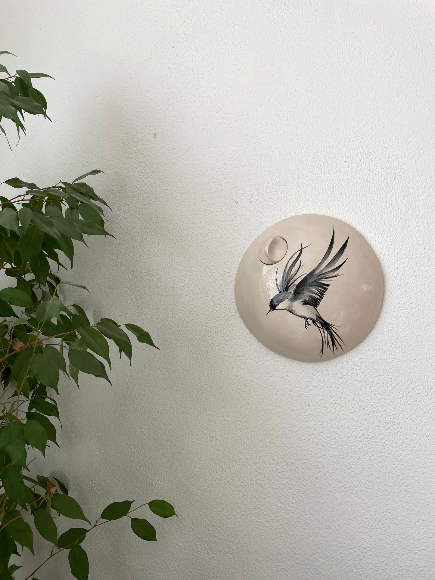 Ronde wandurn met decoratie van een vrije vogel.